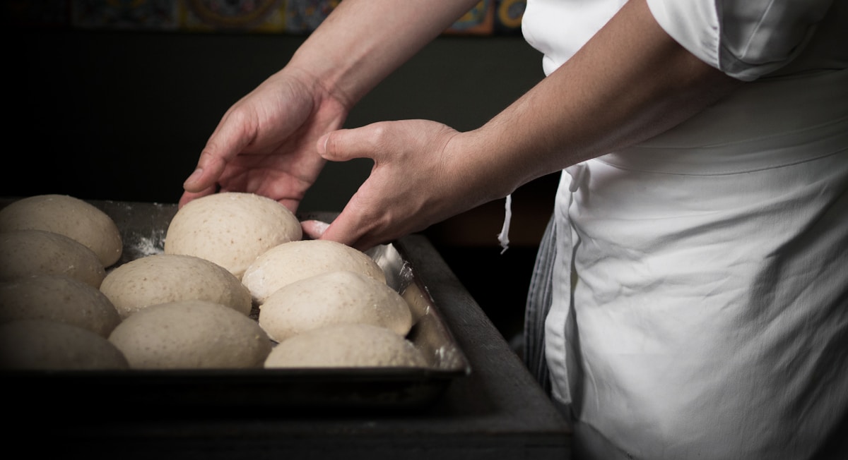 A person placing flatbread dough into a traditional wood-fired oven