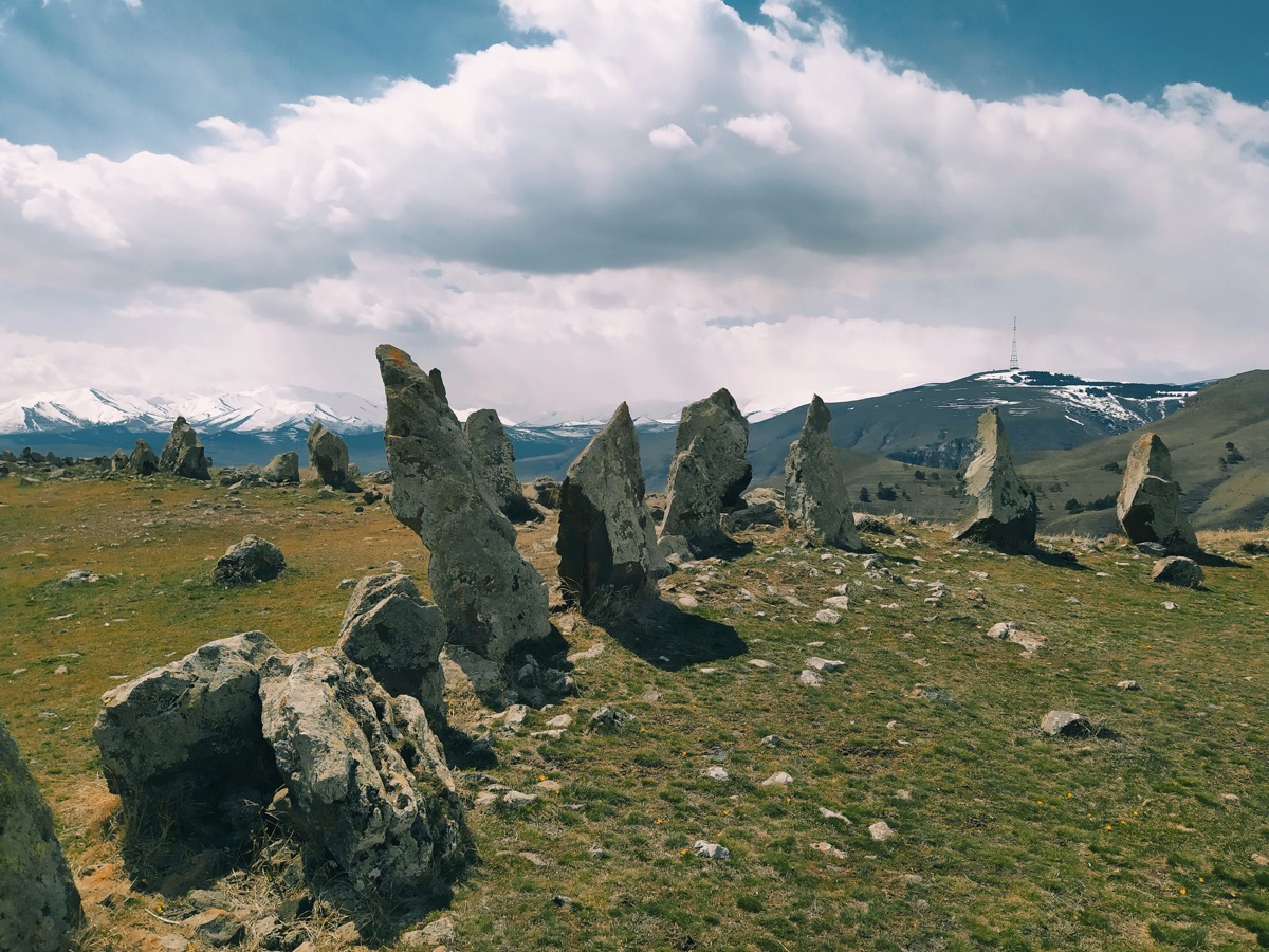 Tall basalt standing stones at Karahunj (Zorats Karer) with snow-capped mountains behind, near Sisian, Syunik Province, Armenia