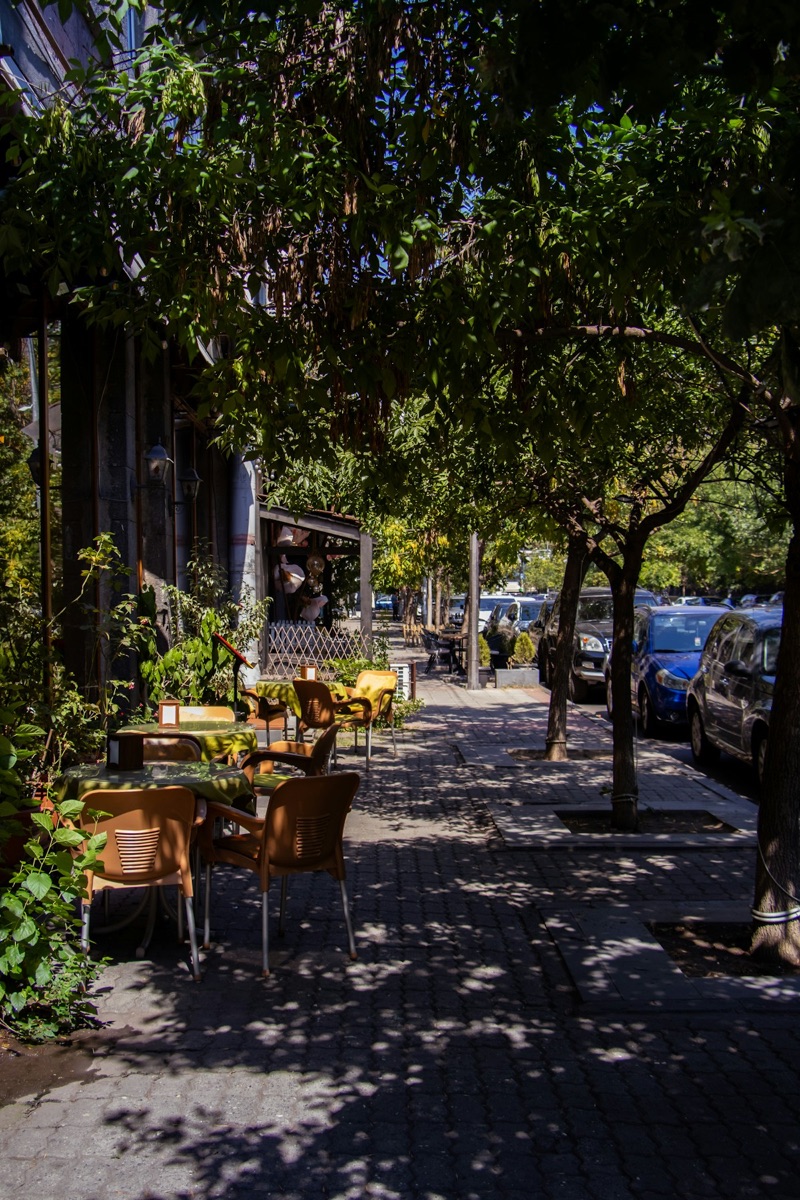 Outdoor café tables and chairs on a shaded Yerevan sidewalk, Armenia