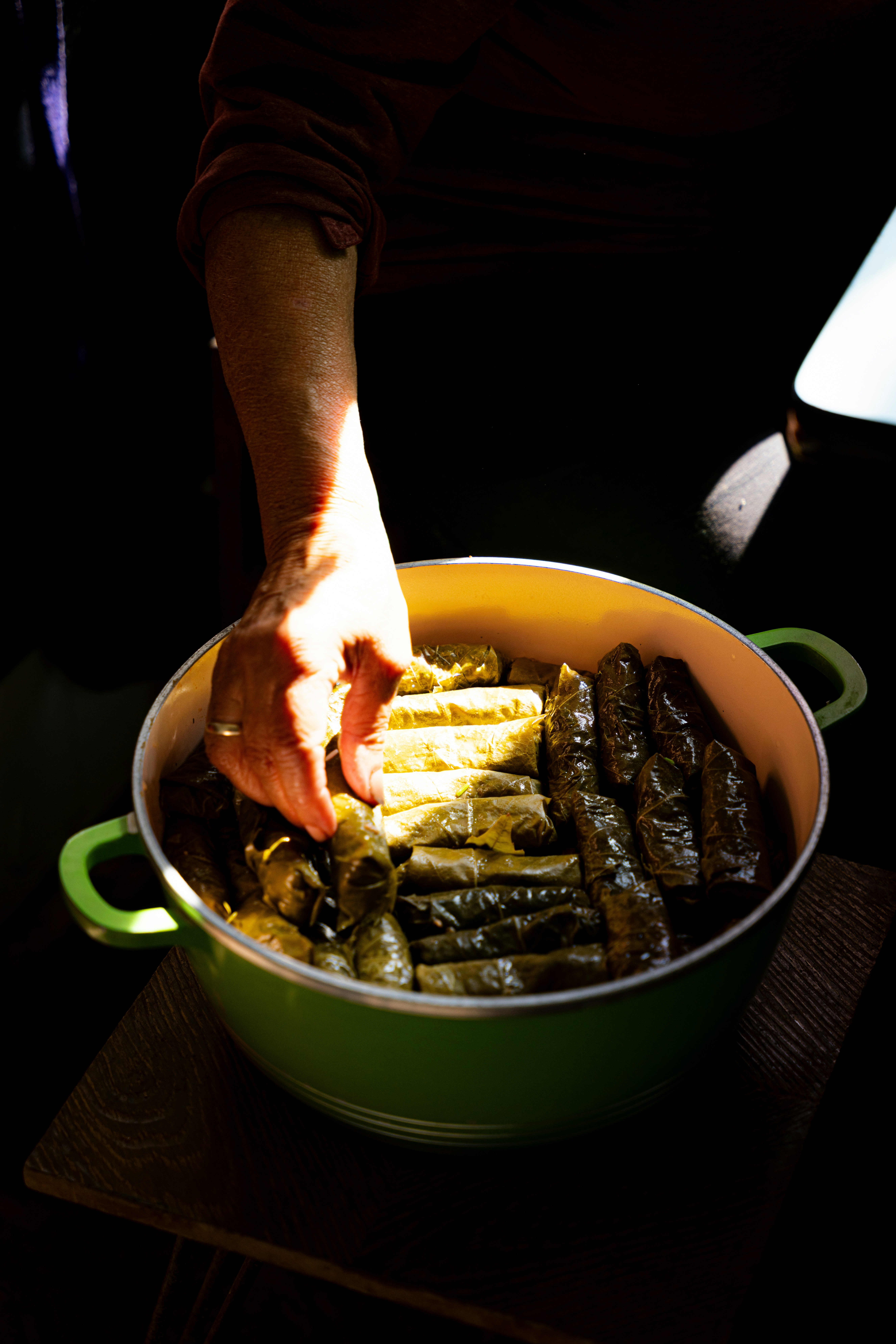 Hands arranging stuffed grape leaves and dolma in a large pot in Armenia