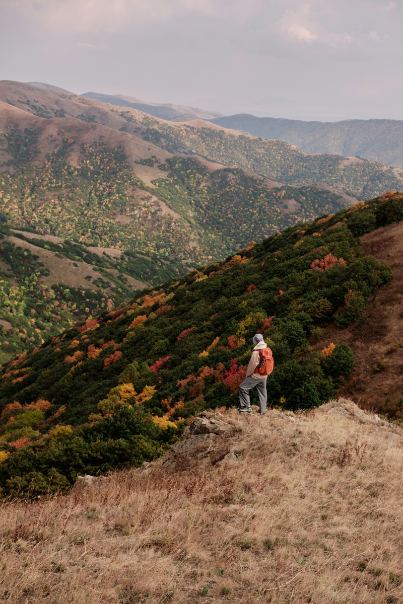 Hiker with orange backpack overlooking Armenia's autumn highland landscape