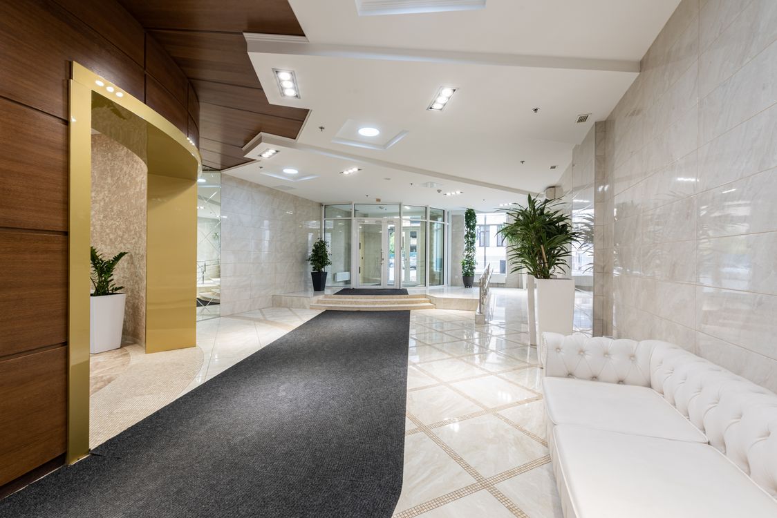 Elegant hotel lobby with marble floors, a tufted white sofa, and gold accents