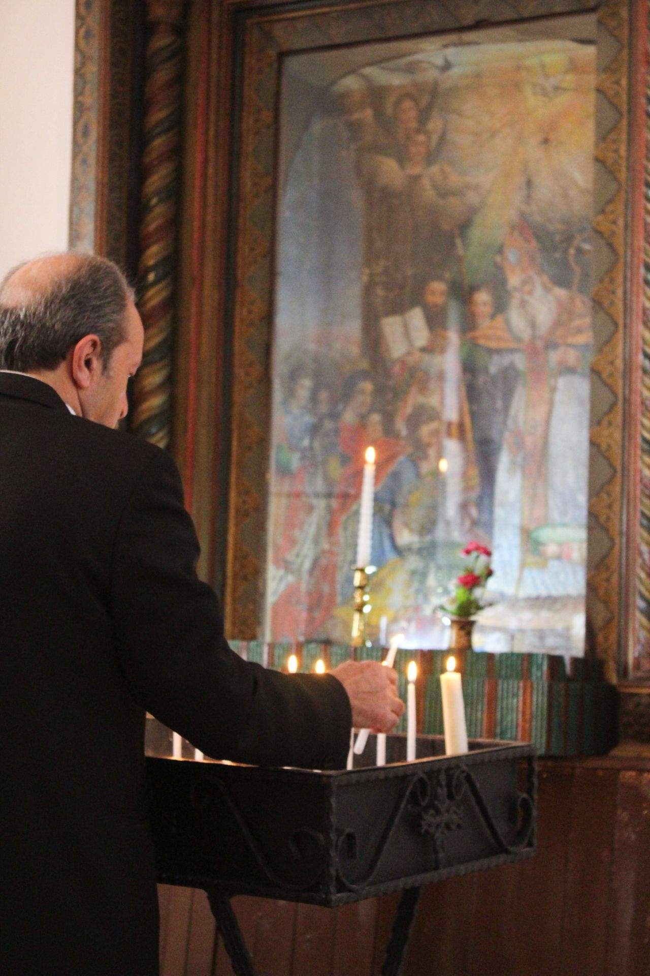 Man lighting candles at a candle stand inside an Armenian church during a ceremony
