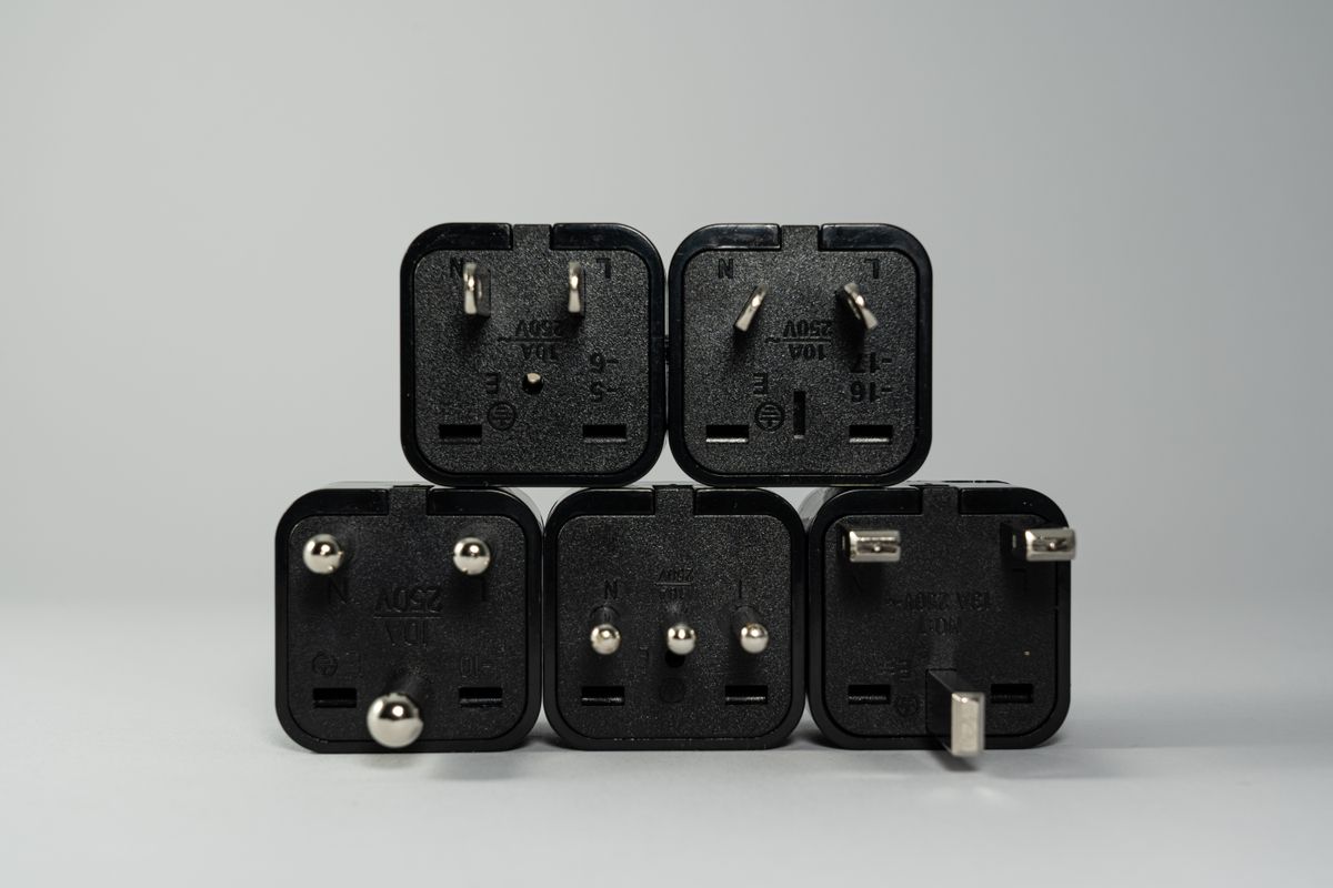 Stack of black travel plug adapters showing different pin layouts